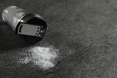 Photo of Salt shaker on grey textured table, closeup. Space for text