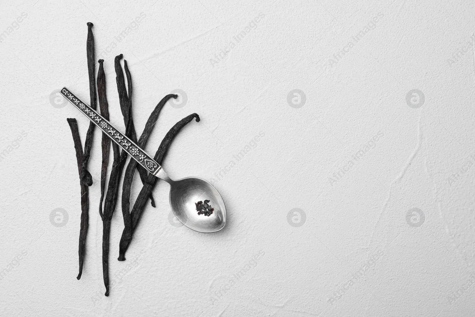 Photo of Aromatic vanilla sticks and spoon on white background