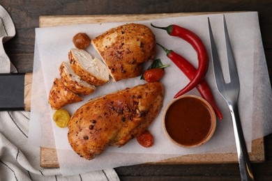 Photo of Baked chicken fillets, chili peppers and marinade on wooden table, top view