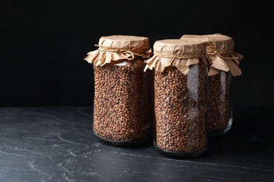 Photo of Buckwheat grains in jars on black table