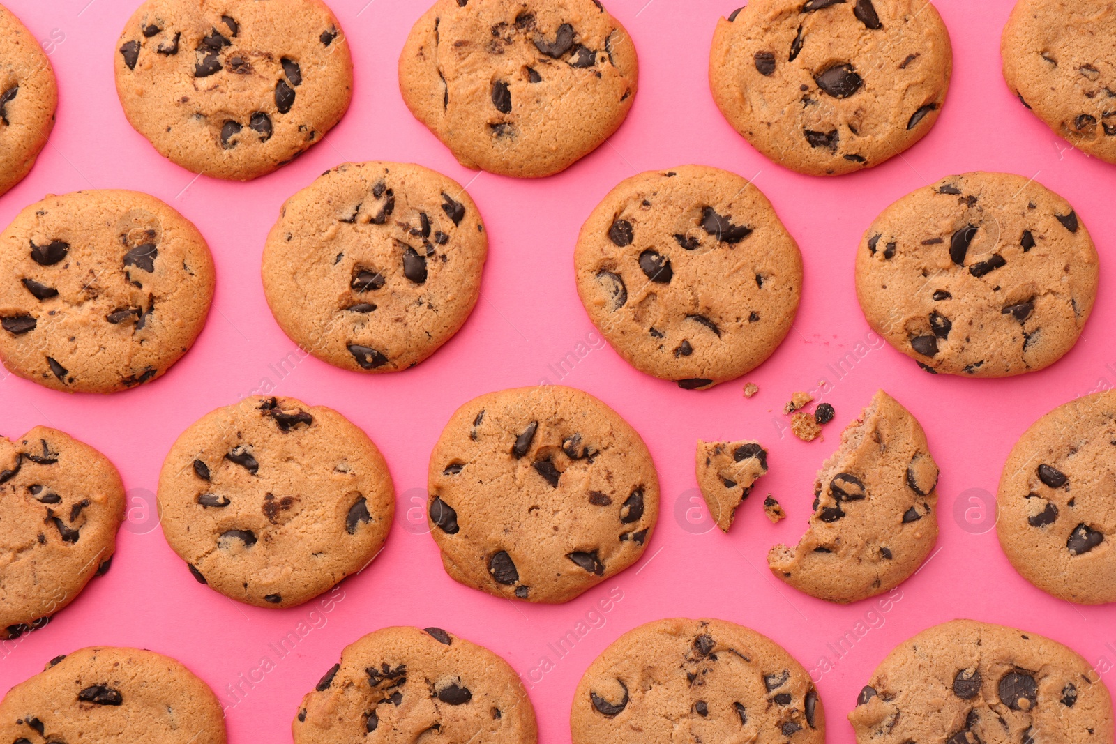 Photo of Many delicious chocolate chip cookies on pink background, flat lay