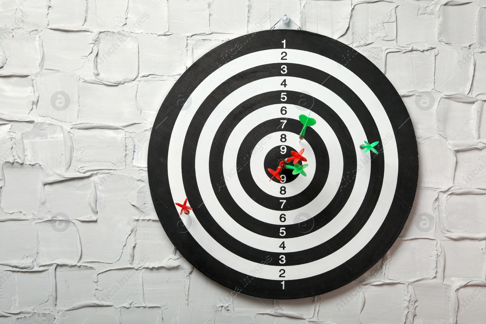 Photo of Arrows hitting dart board on white textured wall