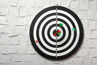 Photo of Arrows hitting dart board on white textured wall