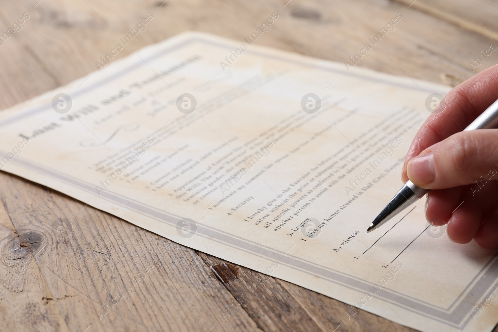 Photo of Woman signing Last Will and Testament at wooden table, closeup