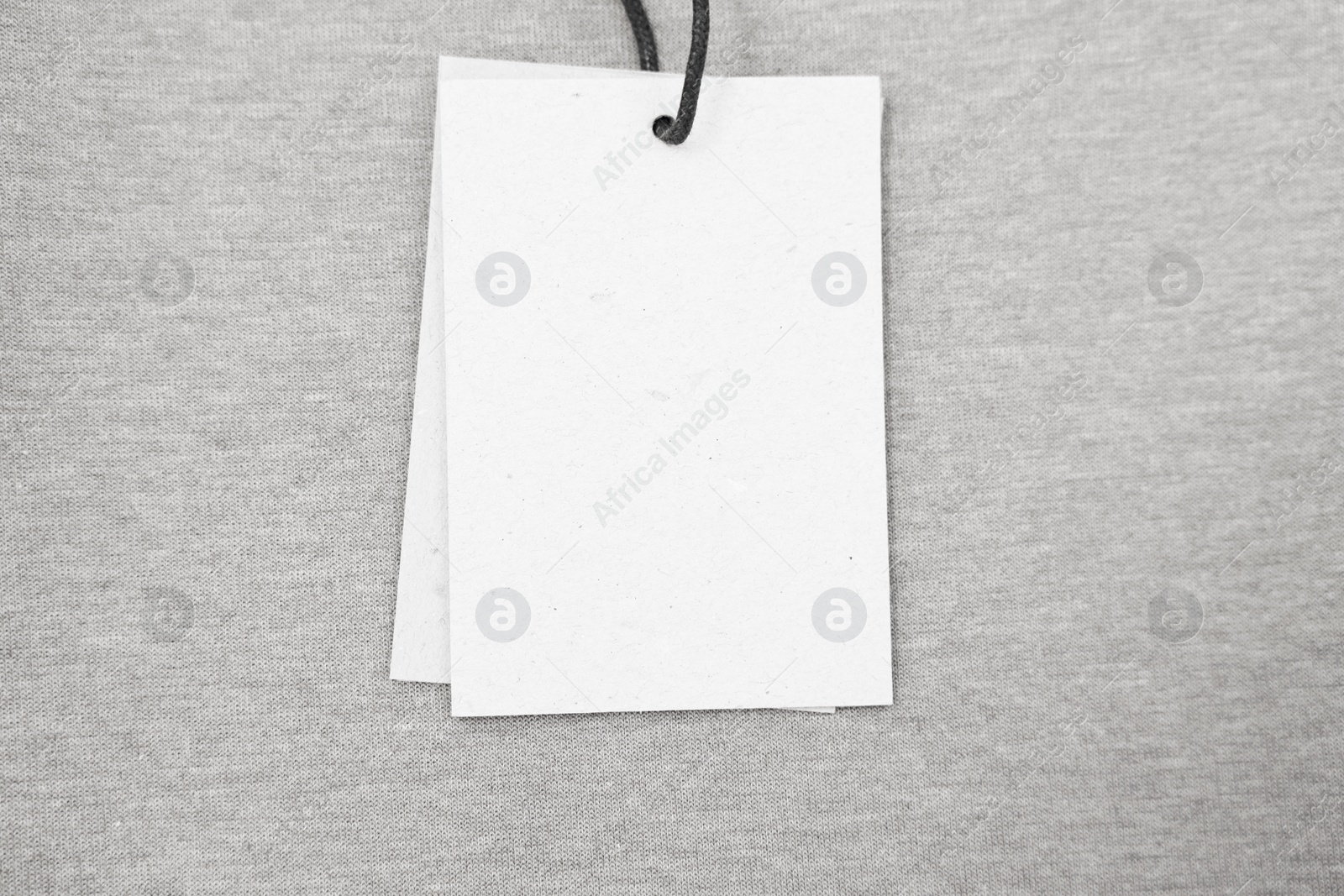 Photo of Cardboard tags on brown garment, top view. Space for text