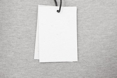 Photo of Cardboard tags on brown garment, top view. Space for text