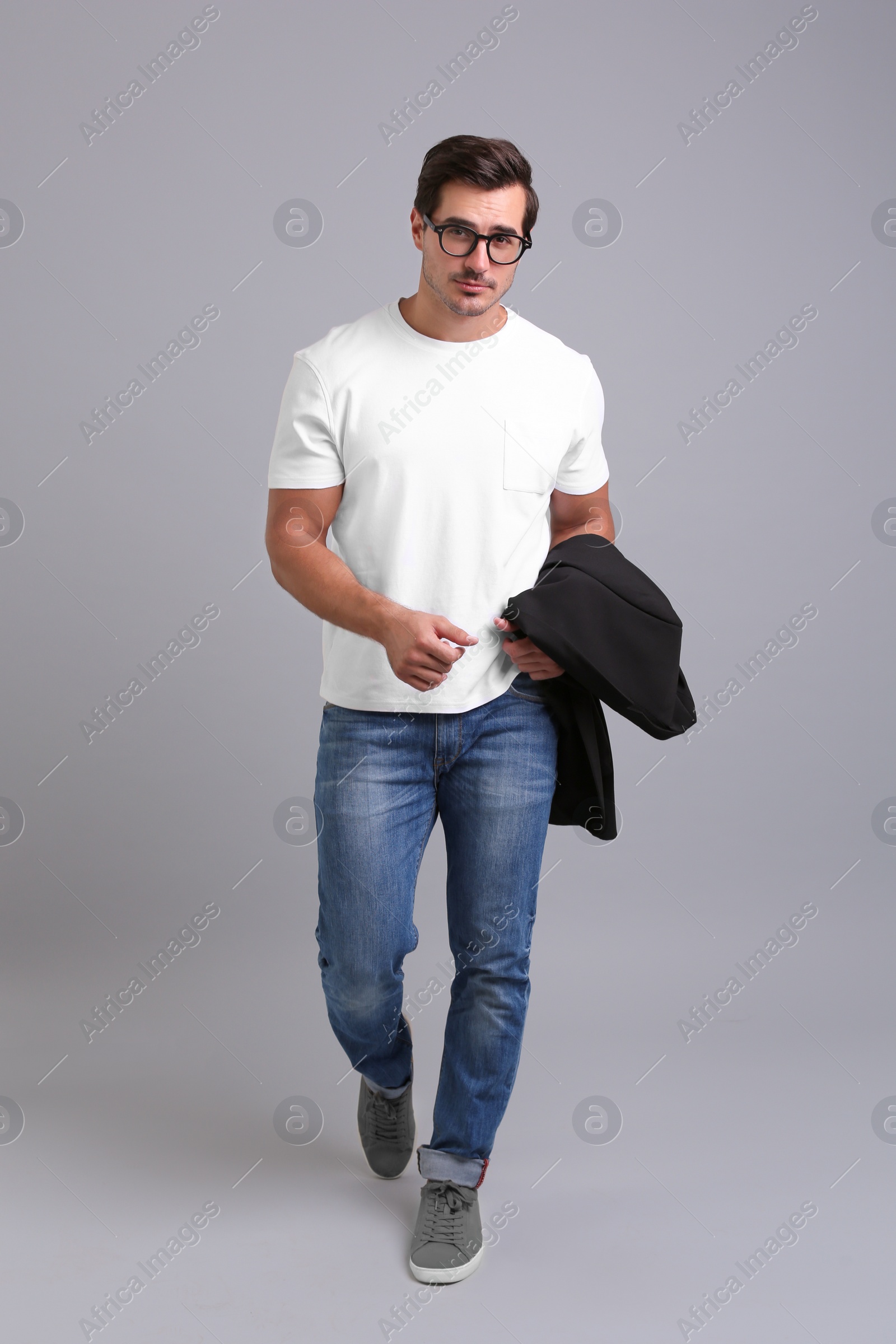 Photo of Handsome young man in casual clothes with black jacket and glasses on grey background