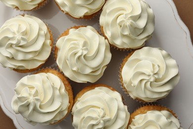 Photo of Tasty vanilla cupcakes with cream on table, flat lay