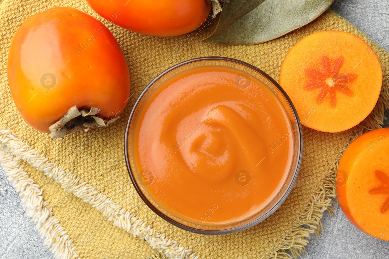 Photo of Delicious persimmon jam in glass bowl and fresh fruits on table, flat lay