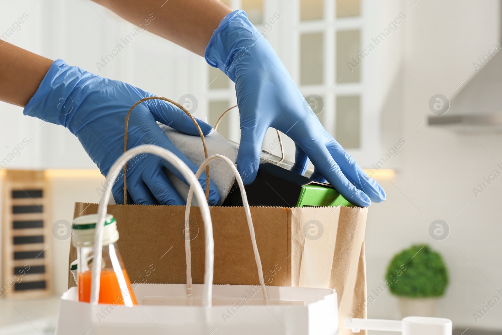 Photo of Woman cleaning newly purchased items with antiseptic wipe indoors, closeup. Preventive measures during COVID-19 pandemic