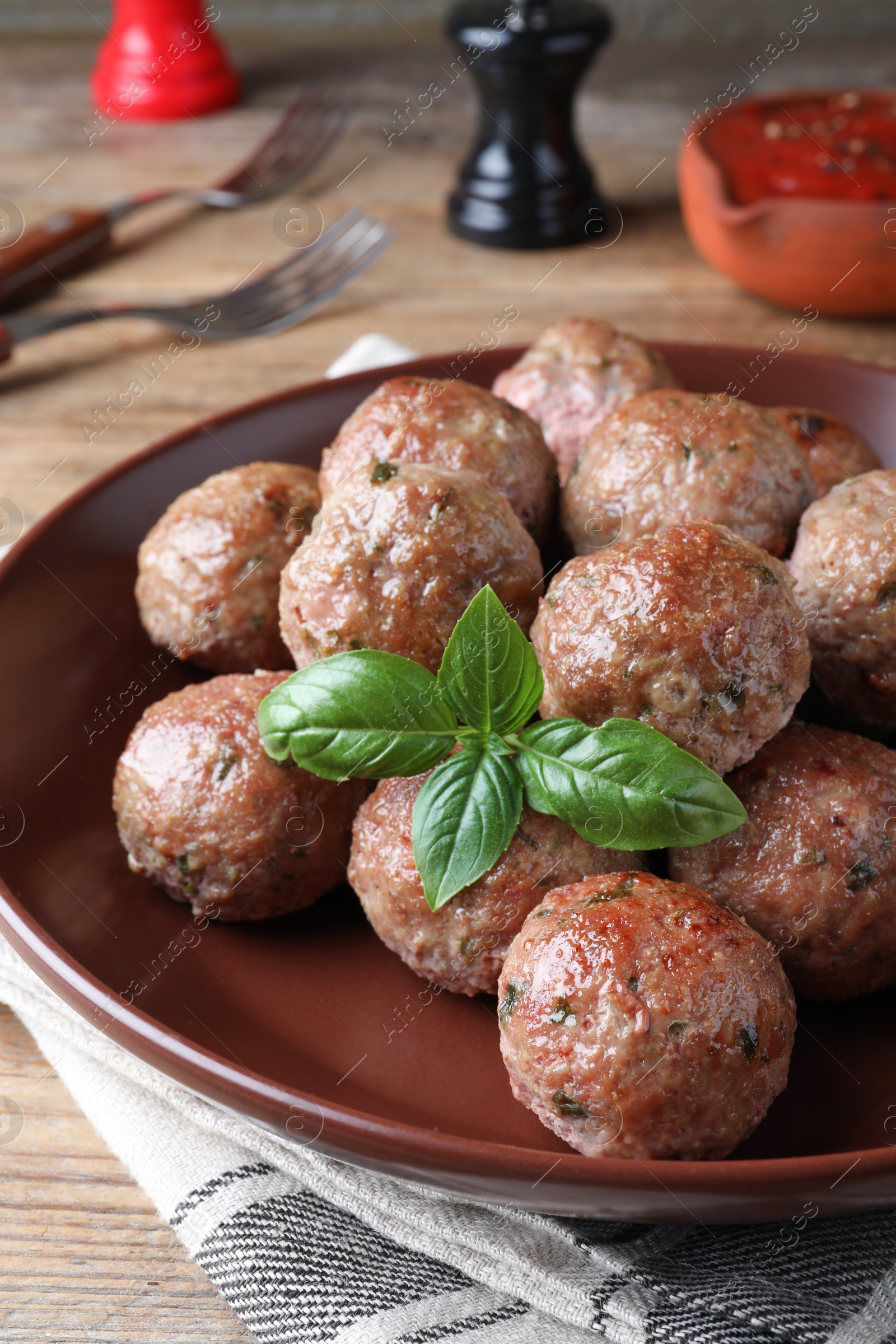 Photo of Tasty cooked meatballs with basil served on wooden table