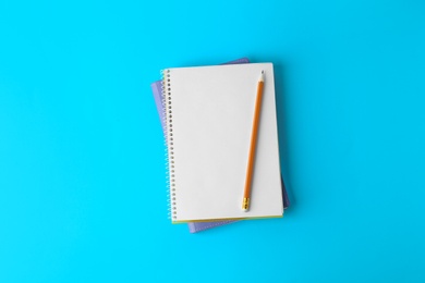 Photo of Notebooks with pencil on light blue background, top view