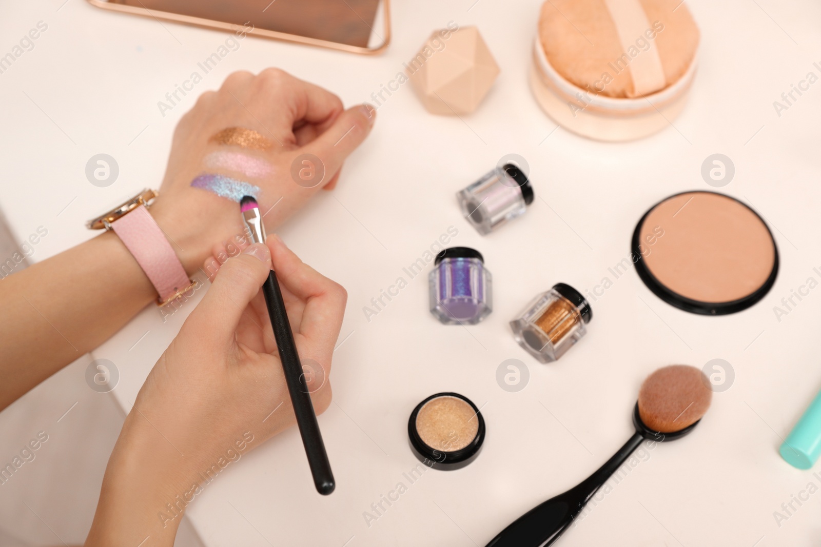 Photo of Beauty blogger doing eyeshadow swatches at table, closeup
