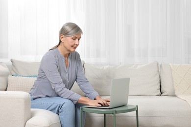 Photo of Beautiful senior woman using laptop at home