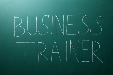 Text BUSINESS TRAINER written on chalkboard. Coaching concept