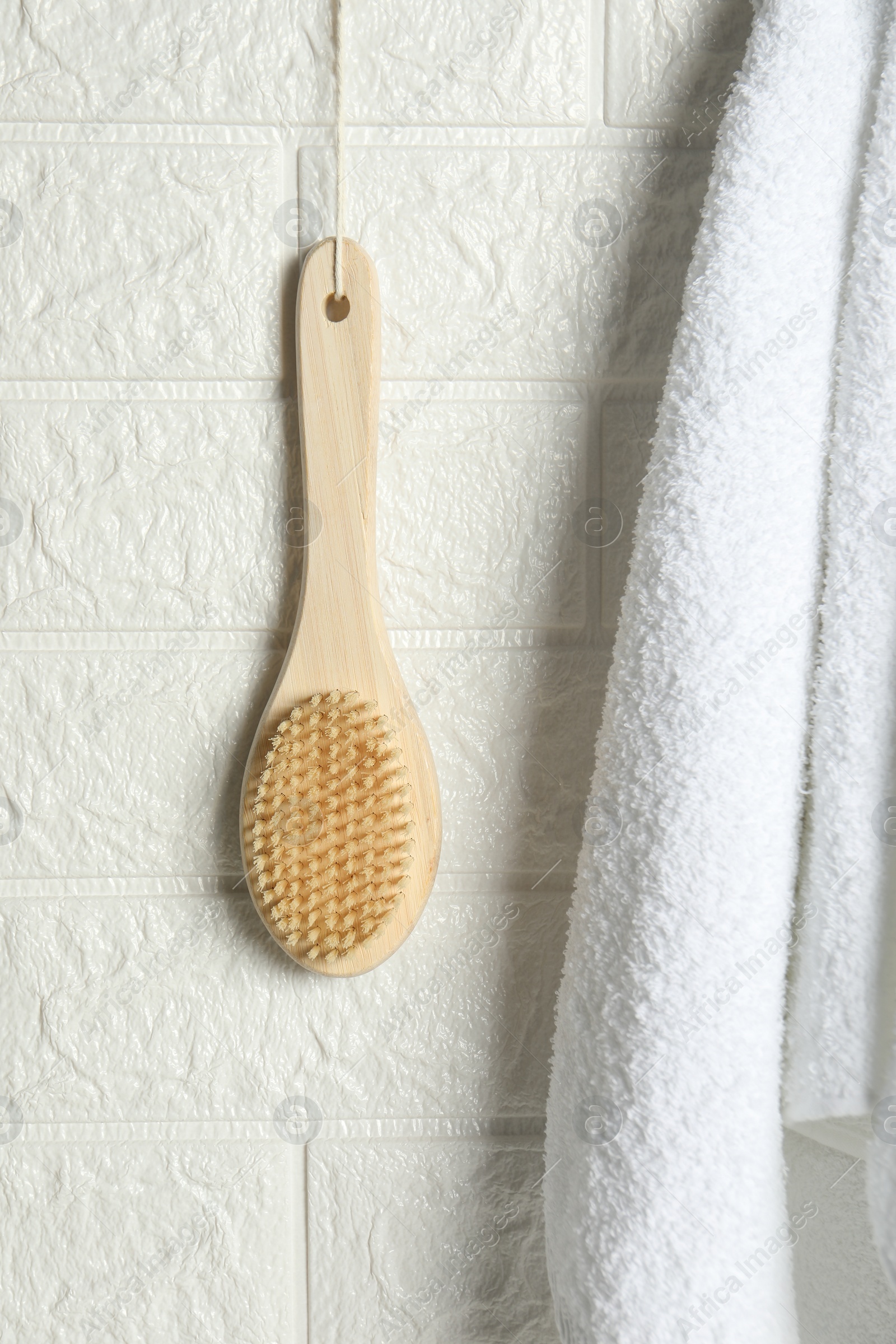 Photo of Bath accessories. Bamboo brush and terry towel on white brick wall