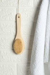 Bath accessories. Bamboo brush and terry towel on white brick wall