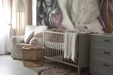 Baby room interior with stylish crib and floral wallpaper