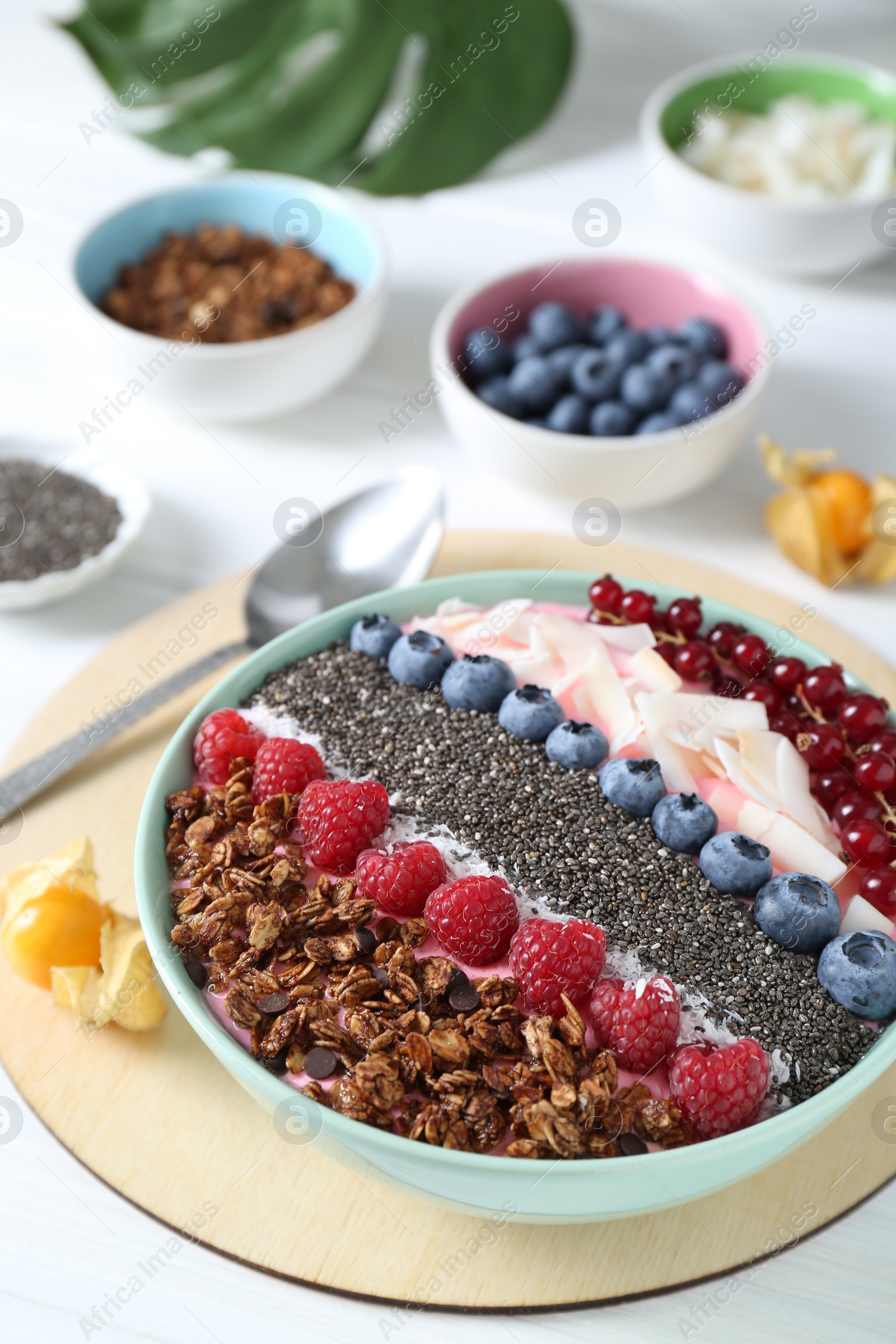 Photo of Tasty smoothie bowl with fresh berries and granola served on white table