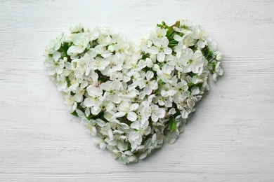 Heart made of beautiful fresh spring flowers on color background, top view