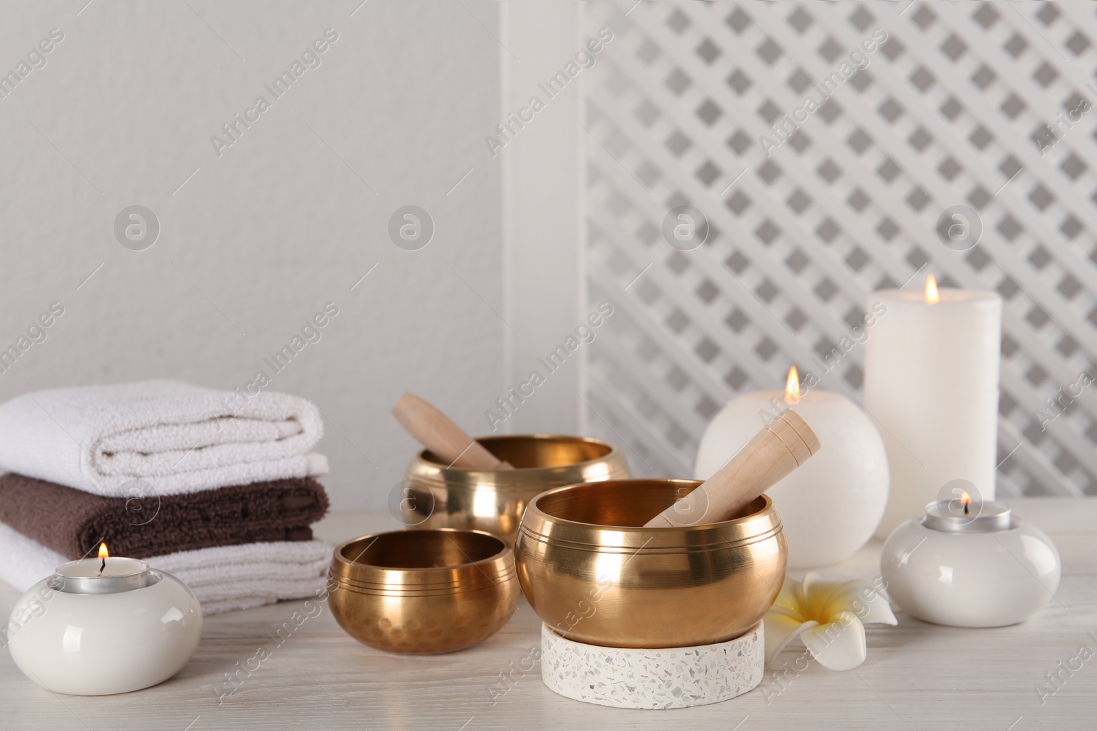 Photo of Composition with golden singing bowls on white wooden table