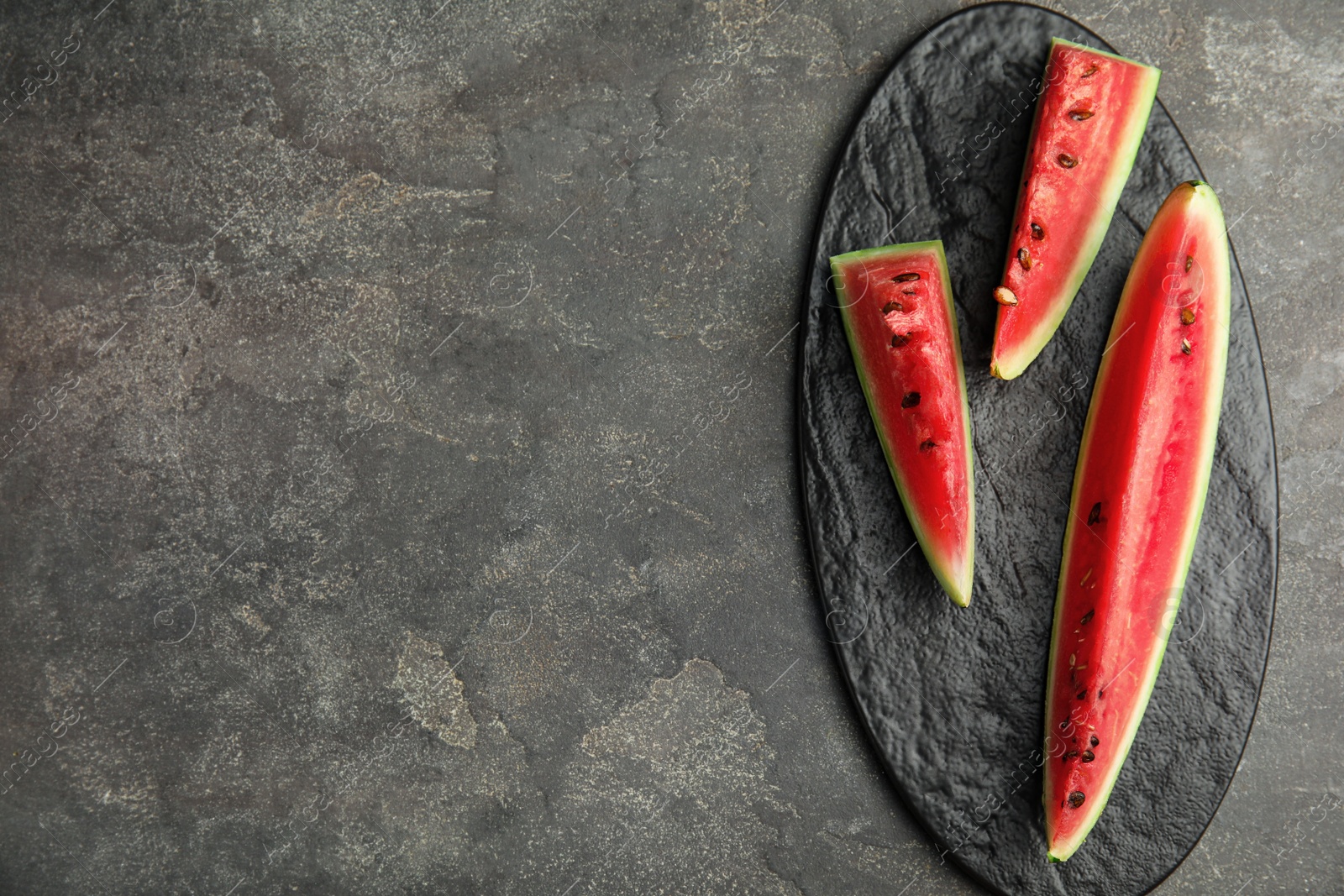 Photo of Yummy watermelon slices on grey table, top view. Space for text