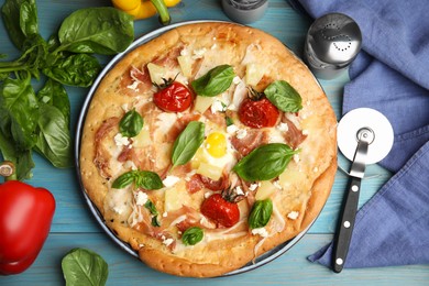 Delicious homemade pita pizza and ingredients on light blue wooden table, flat lay