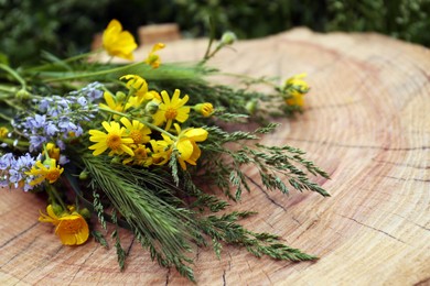 Bouquet of beautiful wildflowers on wooden stump outdoors, closeup