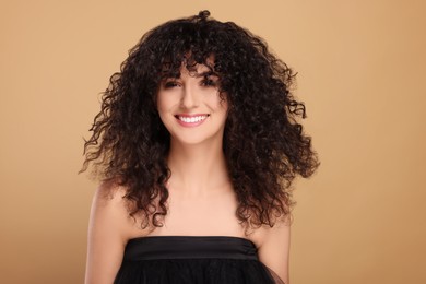 Photo of Beautiful young woman with long curly hair on beige background