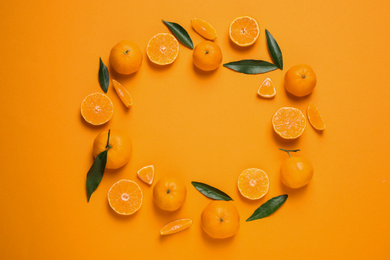 Photo of Frame made of fresh ripe tangerines and space for text on orange background, flat lay. Citrus fruit