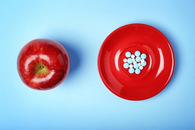 Photo of Apple and plate with weight loss pills on color background, flat lay