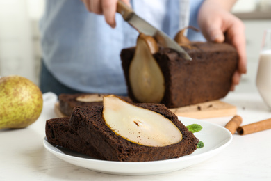 Photo of Slices of tasty pear bread and blurred view of woman with knife on background