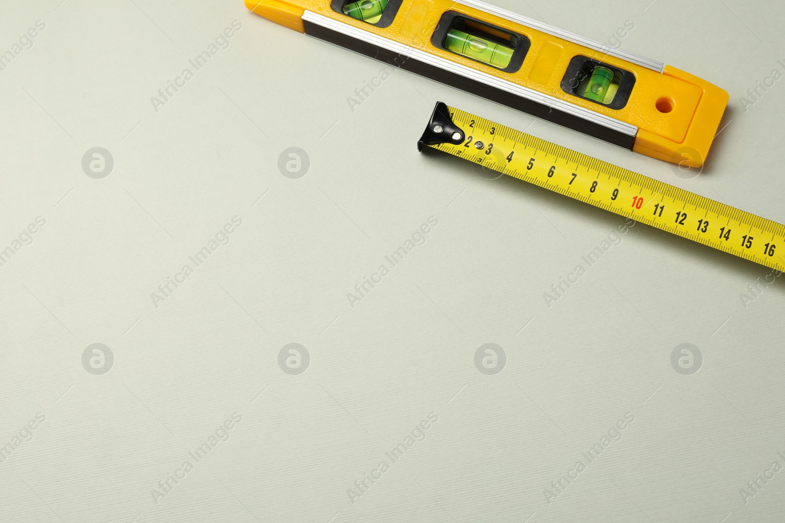 Photo of Building level and tape measure on beige background, top view. Space for text