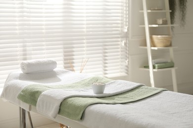 Photo of Massage table with soft towels and sea salt in spa salon