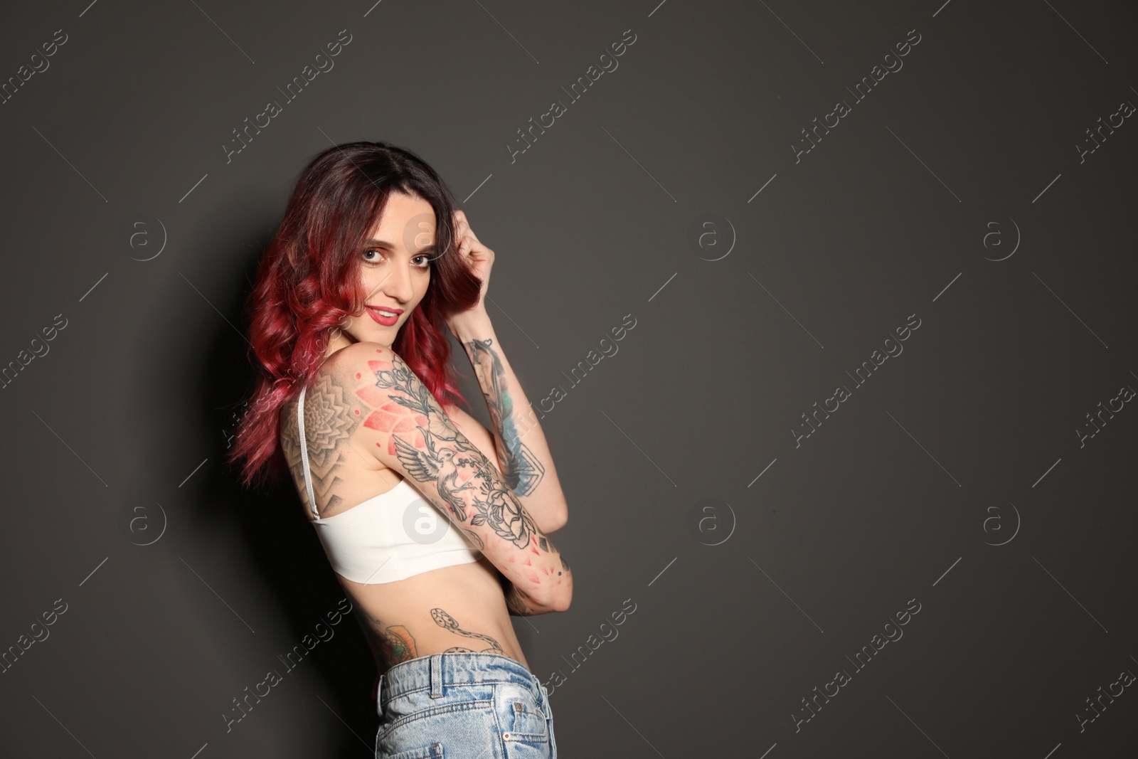 Photo of Beautiful woman with tattoos on body against black background. Space for text