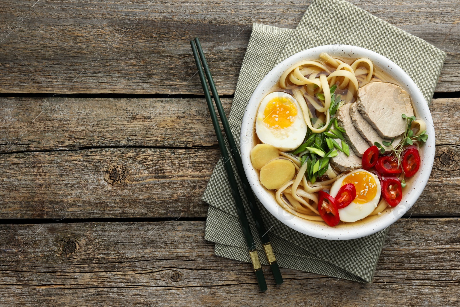 Photo of Delicious ramen in bowl and chopsticks on wooden table, flat lay with space for text. Noodle soup