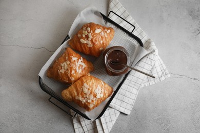 Photo of Delicious croissants with almond flakes and chocolate paste on light grey table, top view