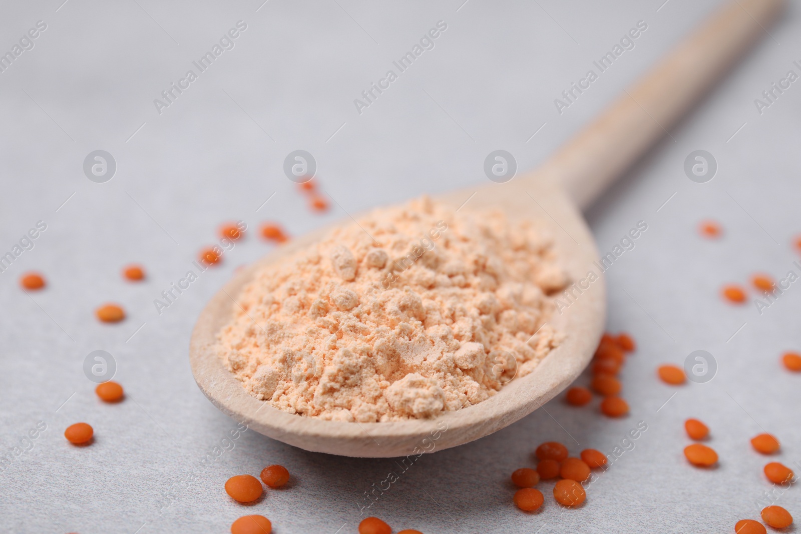 Photo of Spoon of lentil flour and seeds on white table, closeup