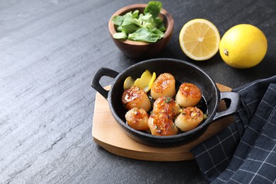 Photo of Delicious fried scallops, lemons and corn salad on dark gray textured table, space for text