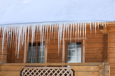 Photo of House with icicles on roof. Winter season