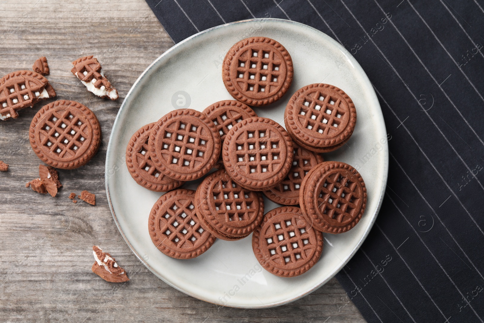 Photo of Tasty chocolate sandwich cookies with cream on wooden table, flat lay