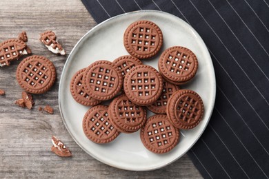 Photo of Tasty chocolate sandwich cookies with cream on wooden table, flat lay