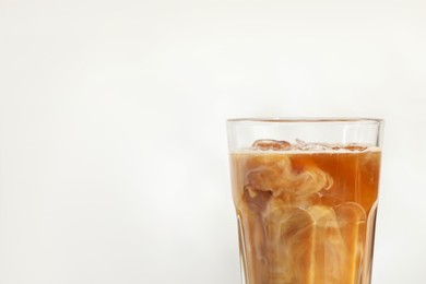 Photo of Refreshing iced coffee with milk in glass on white background, closeup. Space for text