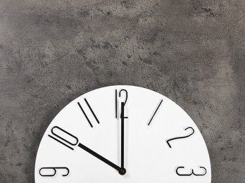 Photo of Stylish analog clock hanging on grey wall, space for text