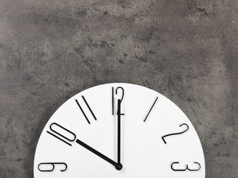 Stylish analog clock hanging on grey wall, space for text