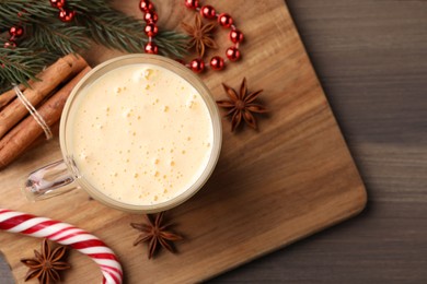 Photo of Glass of delicious eggnog and ingredients on wooden table, flat lay. Space for text