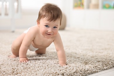 Cute baby boy crawling on carpet at home. Space for text