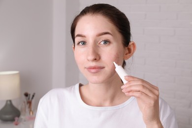 Woman with acne problem applying cream at home