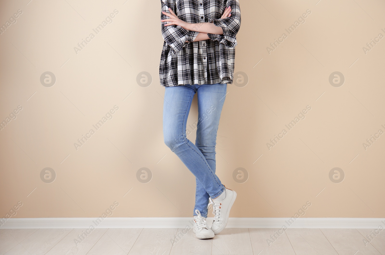 Photo of Young woman in stylish jeans near light wall