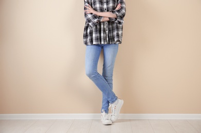 Photo of Young woman in stylish jeans near light wall